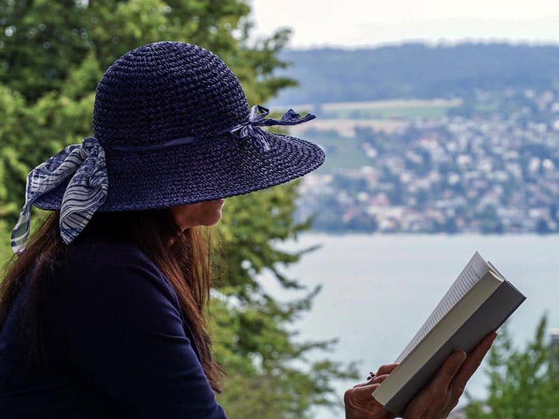 A woman reading from a park overlooking the water