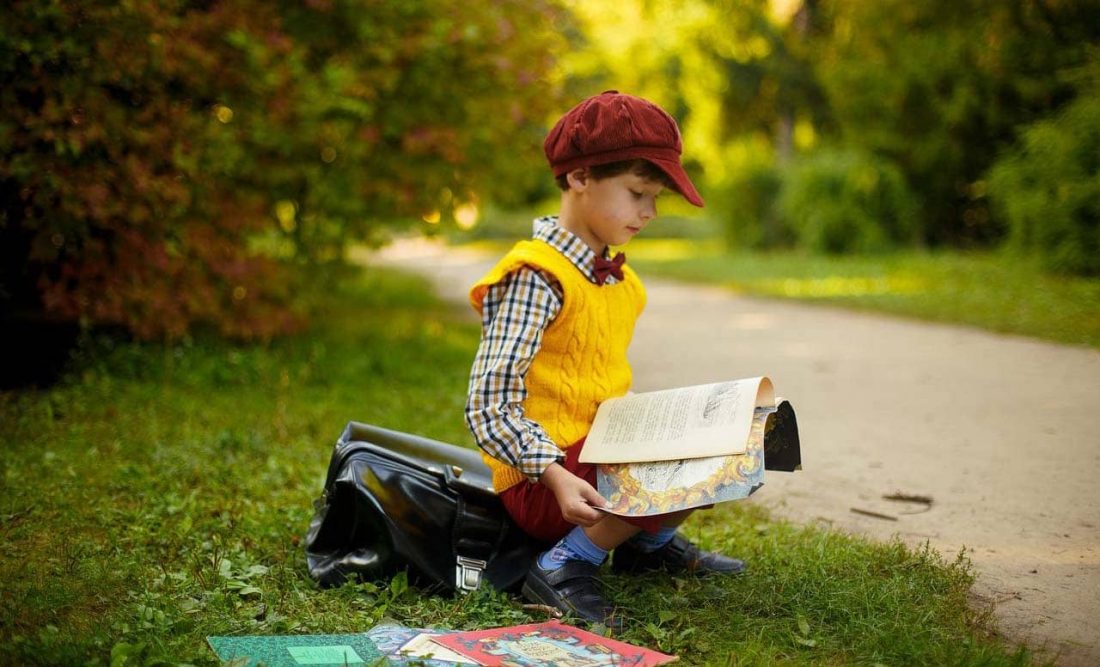A young boy reading by the roadside